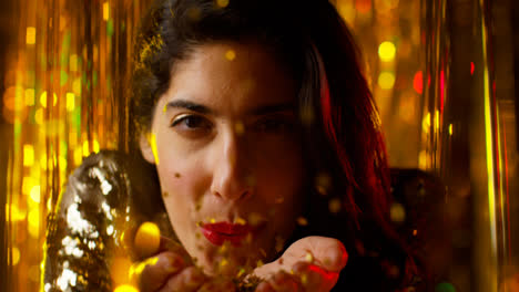 Woman-Celebrating-At-Party-Or-Club-Blowing-Handful-Of-Gold-Glitter-Towards-Camera-1